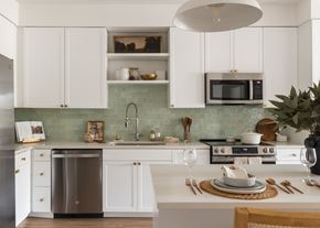 Austin apartment for rent - A modern kitchen with white cabinets and a green backsplash.